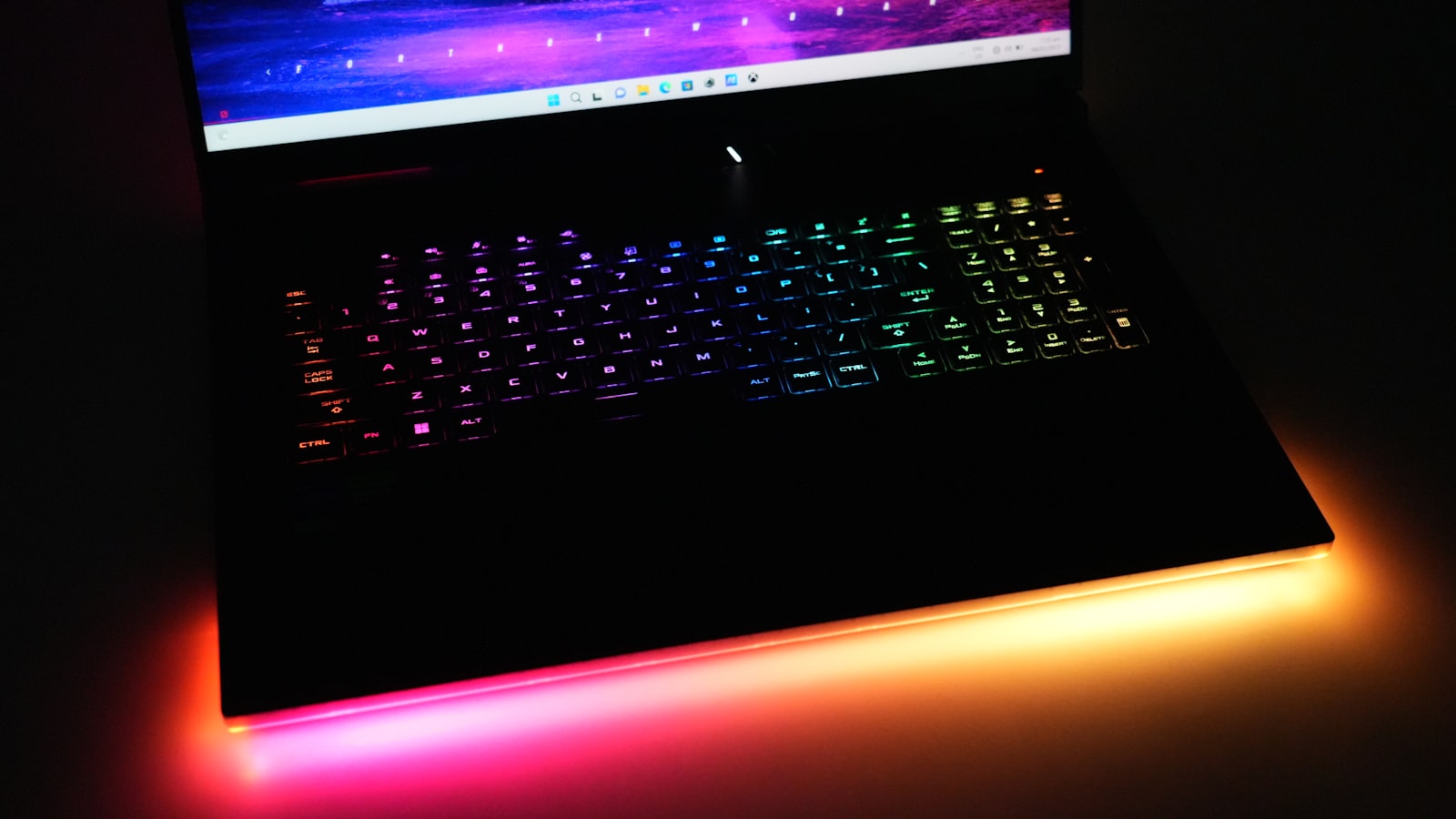 A laptop with a glowing RGB backlit keyboard in a dark room
