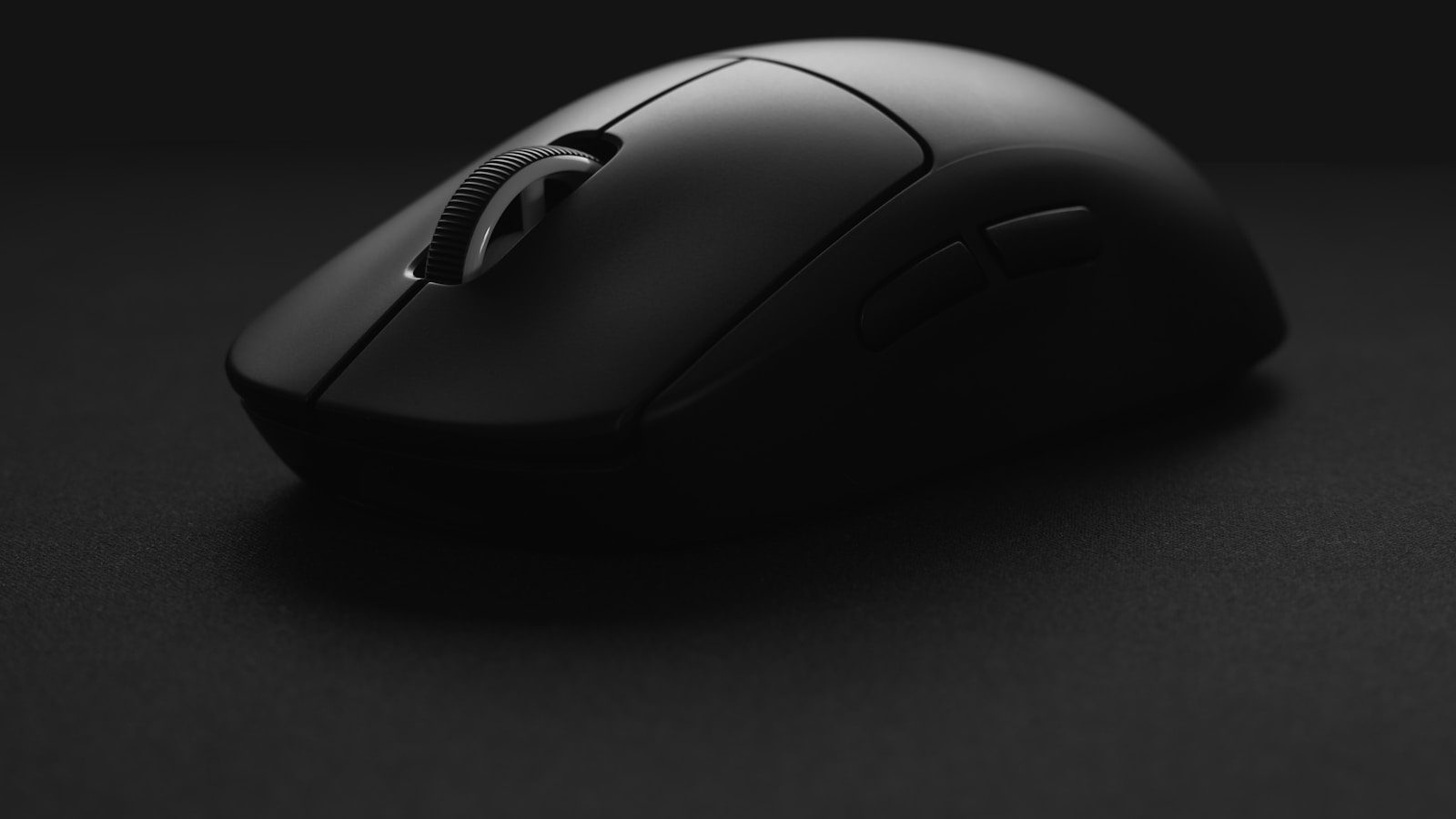 A dark wireless mouse photographed close-up against a black background